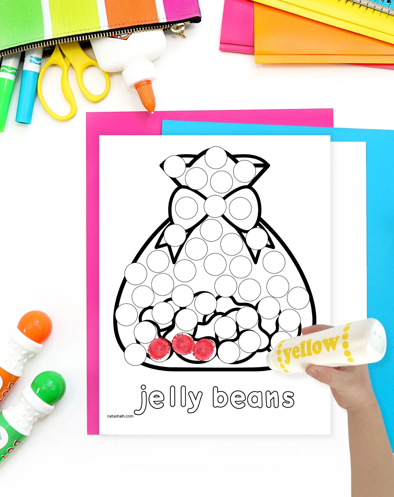 a hand with a dot marker preparing to color a sheet showing a bag of jelly beans