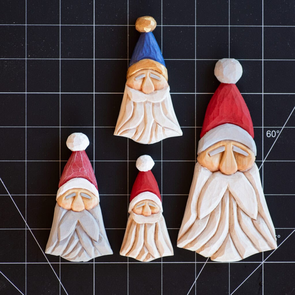 four wood carved Santas on a grid mat