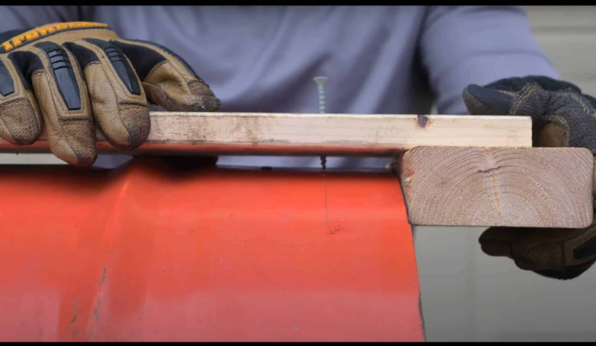 Photo is of a man scribing a line using a screw to mark out 1.5 inches on a 55 gallon drum.