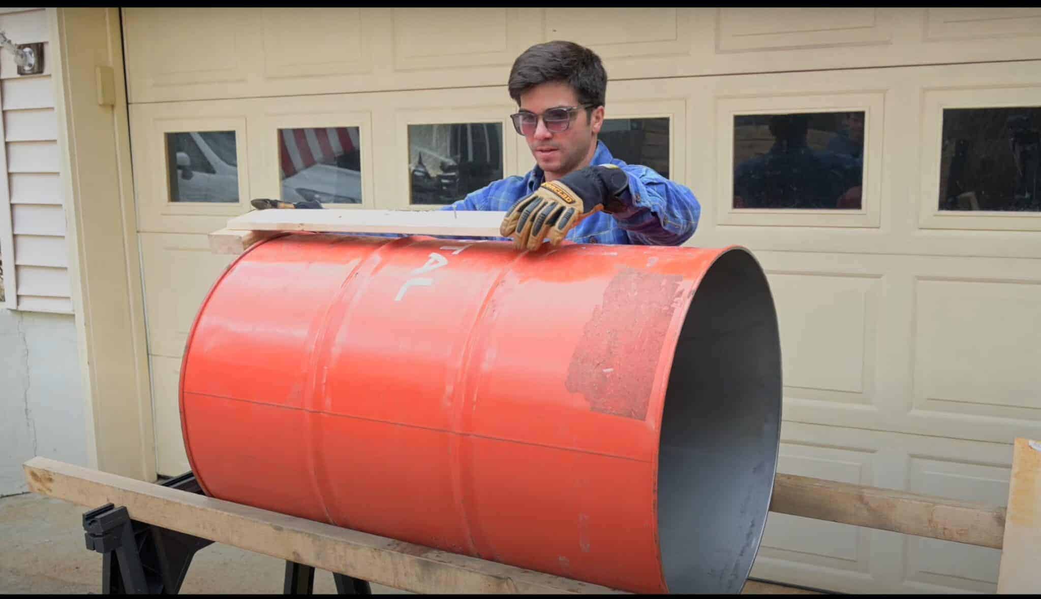 Photo is of a man scribing a line on a 55 gallon while it is on 2 2x4s to hold it stable.