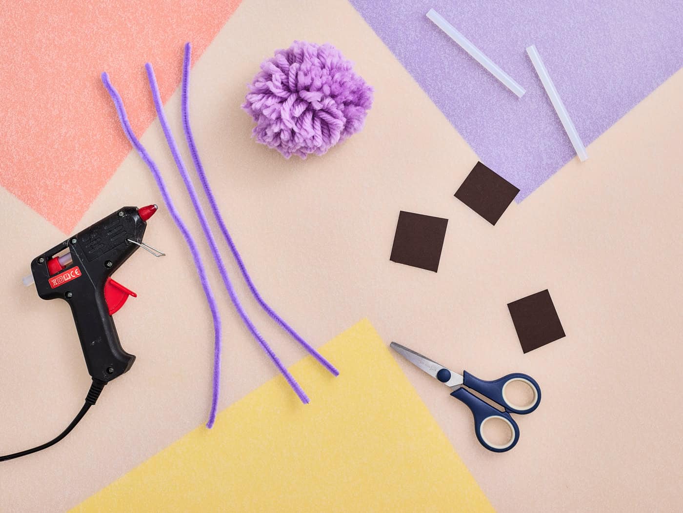 materials for making a pom pom axolotl craft including a pompom, fuzzy sticks, cardboard, and glue sticks
