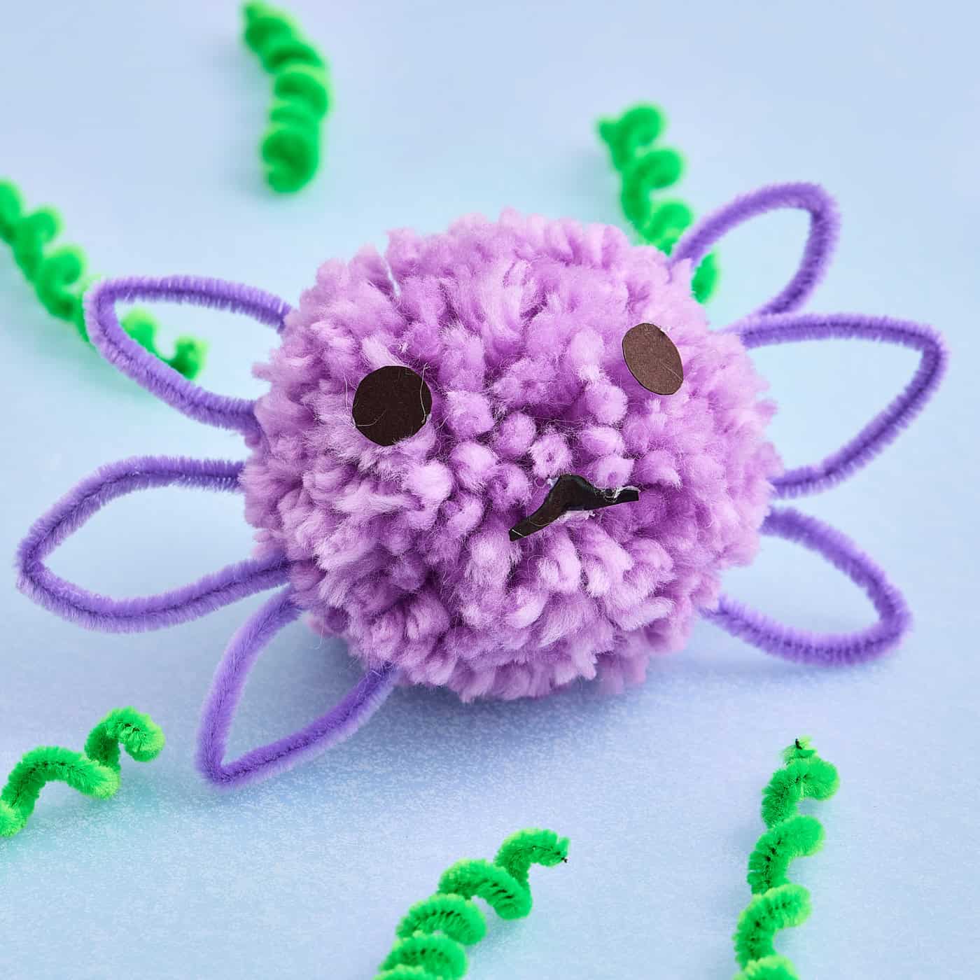 a cute axolotl craft made with purple pom pom and pipe cleaners