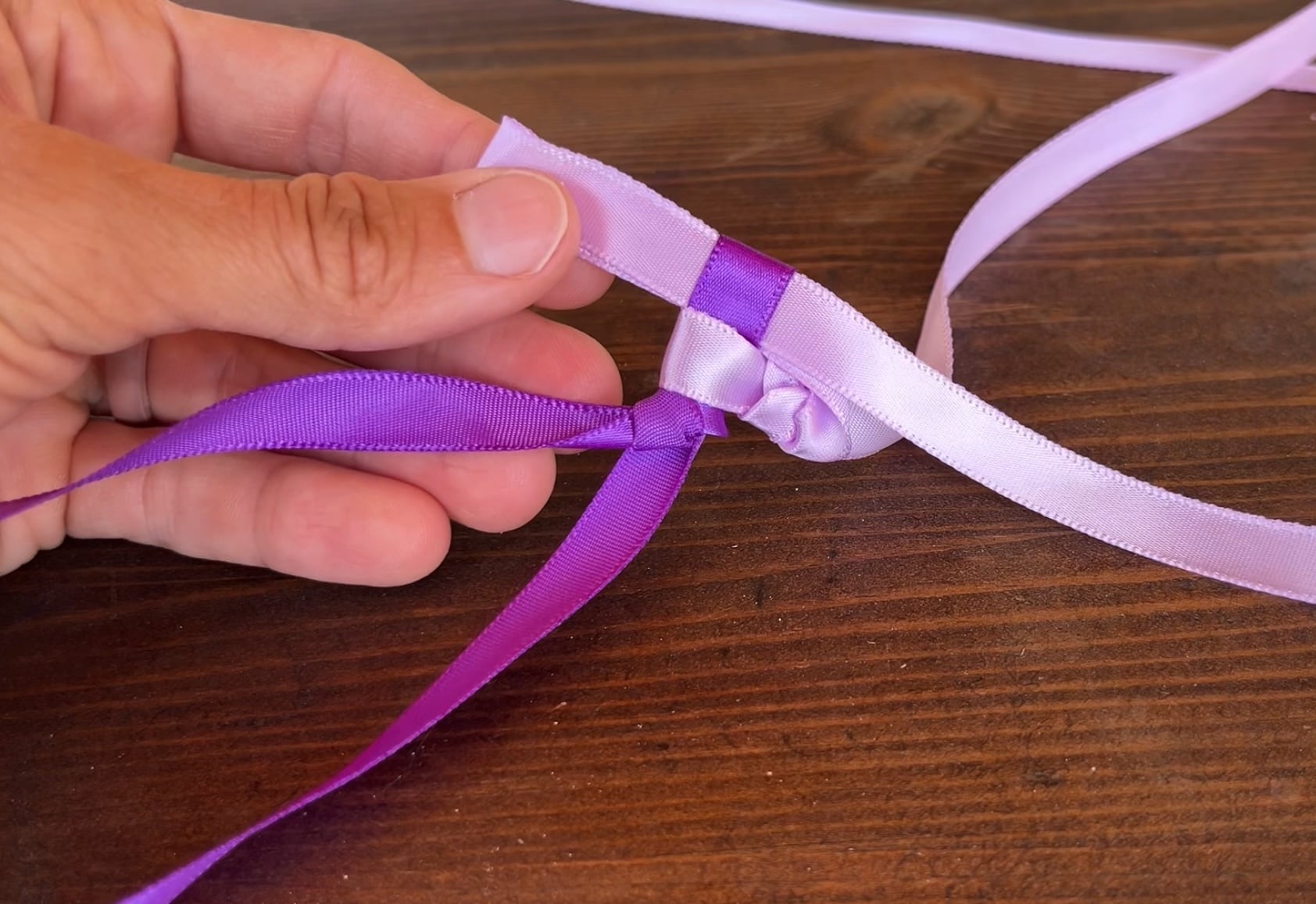looping ribbon through other pieces of ribbon to make a ribbon lei in the Hawaiian style