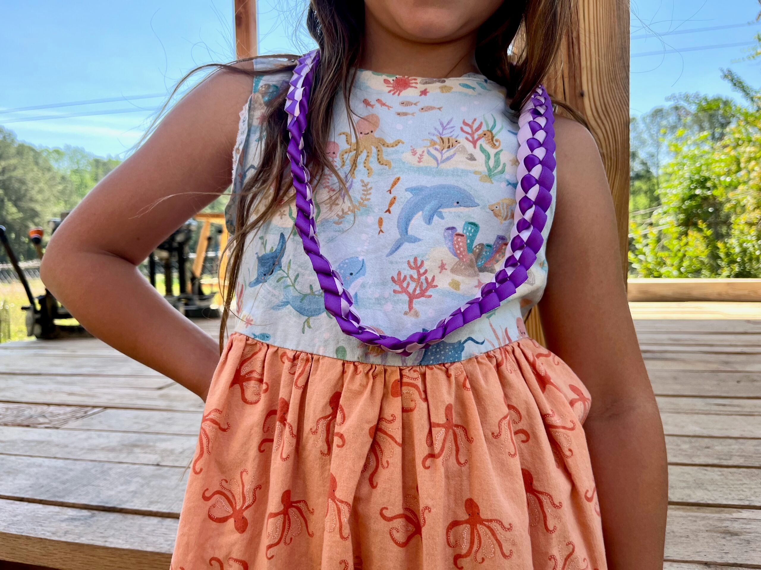a child wearing a purple ribbon lei