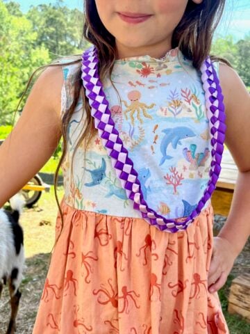 a child wearing a purple ribbon lei for a kindergarten graduation