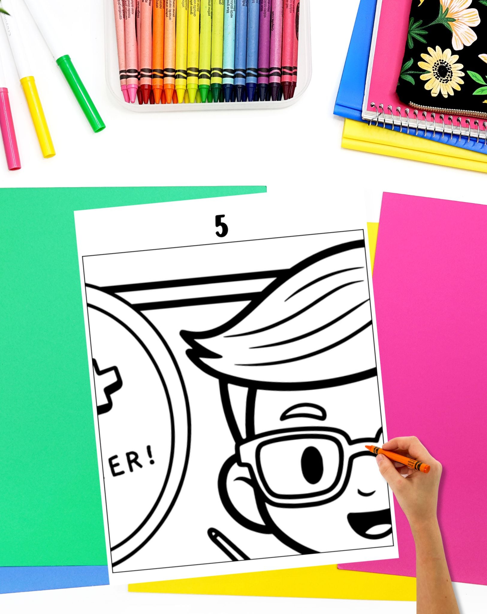 a hand with a crayon preparing to color a piece from a collaborative poster.