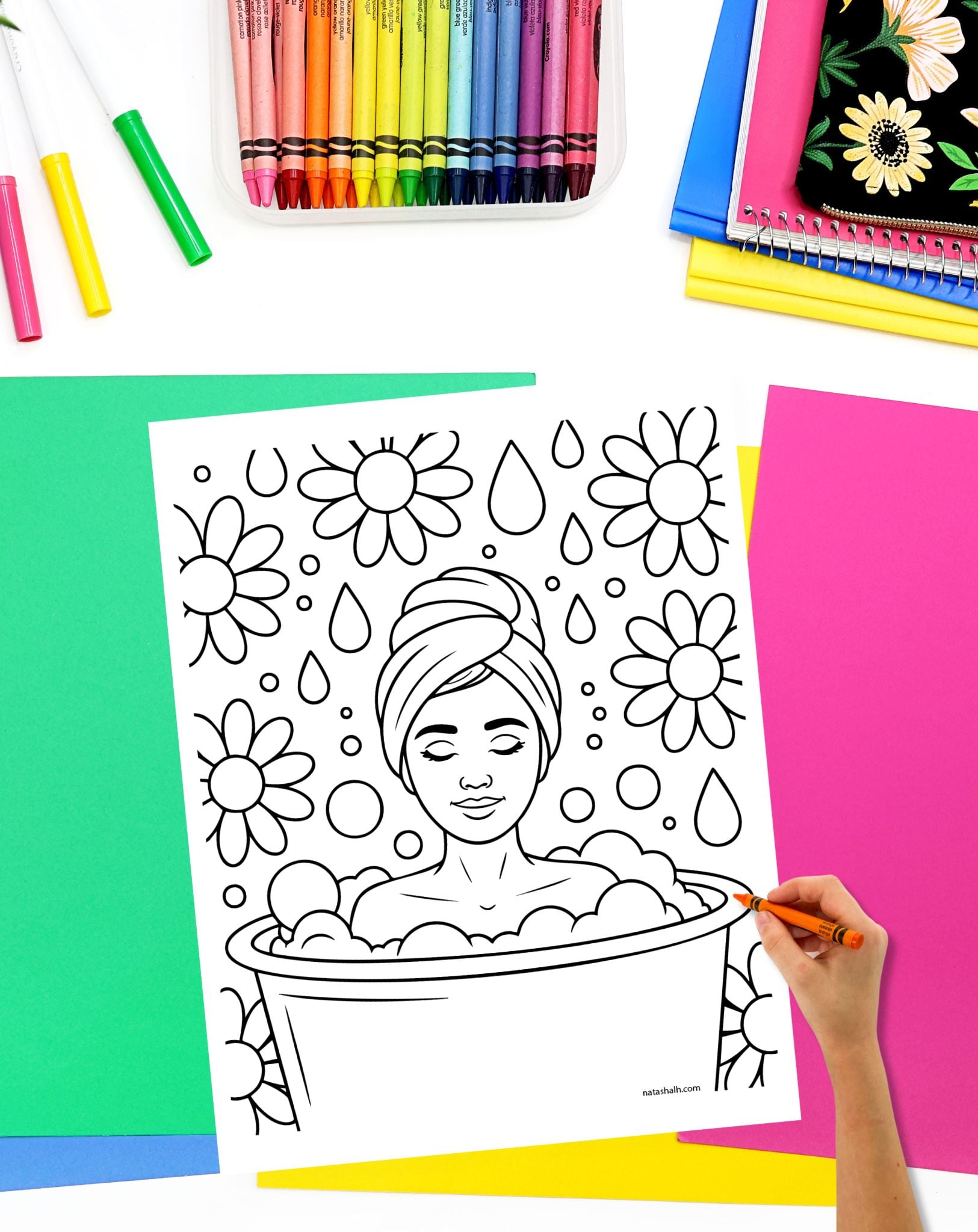 a hand with a crayon preparing to color a coloring page with a woman relaxing in a bubble bath