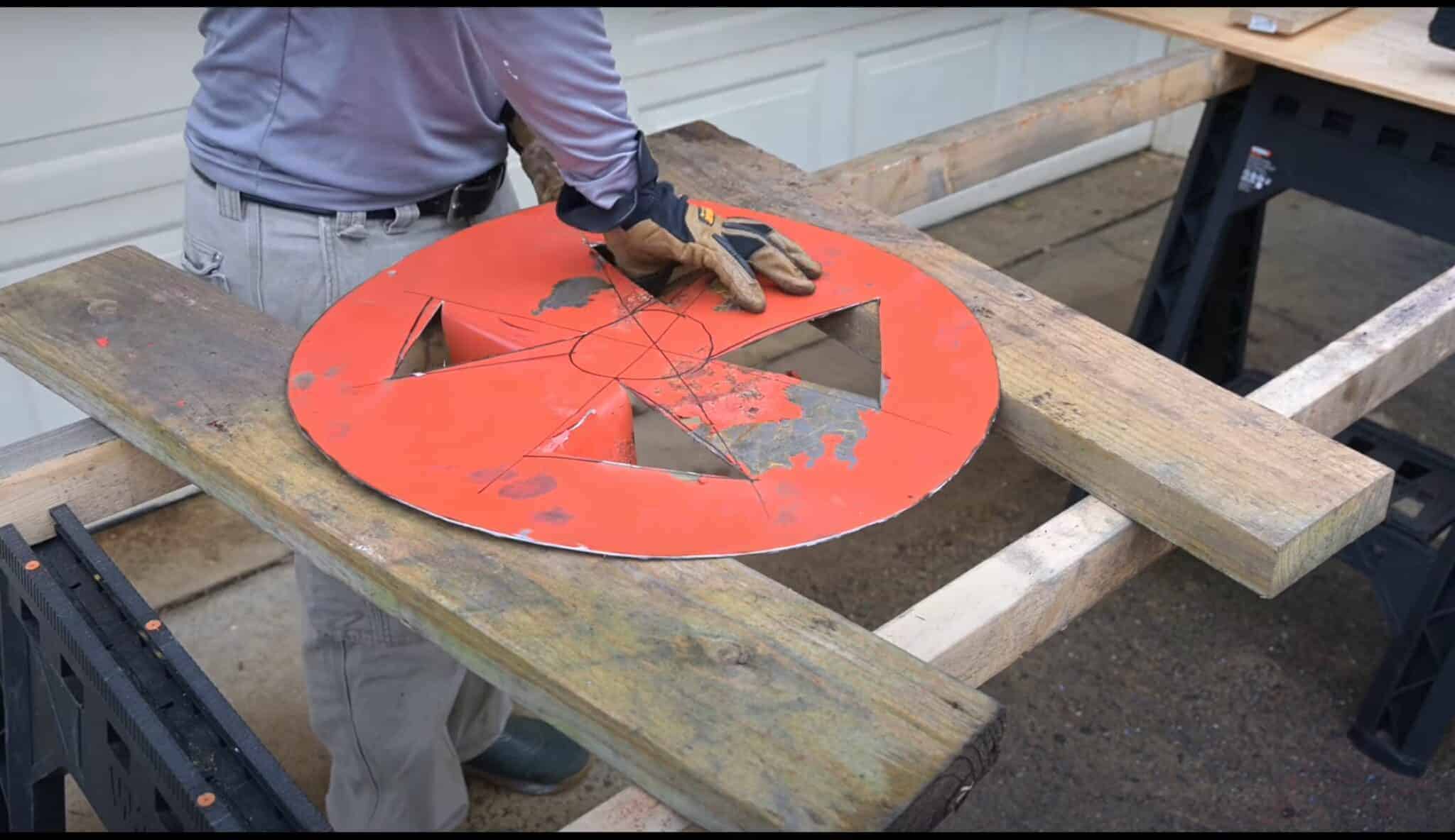 Photo is of a man folding out the grate holes for a smokeless firepit.
