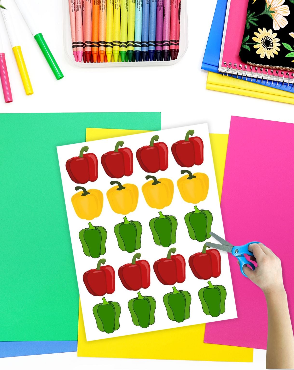 a child's hand with scissors preparing to help cut out bell pepper pieces for a dramatic play set