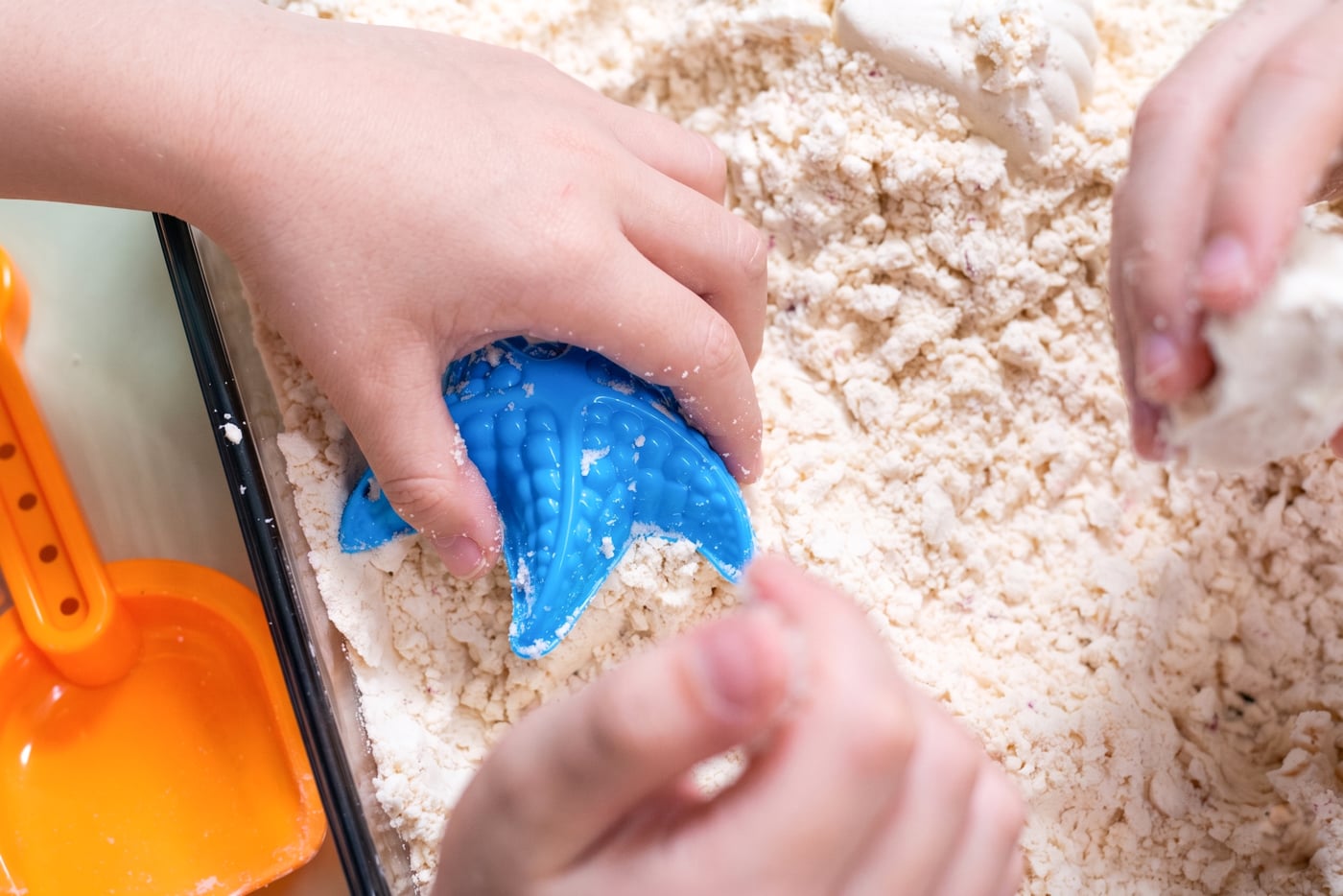 a child using diy moon sand with a blue starfish toy
