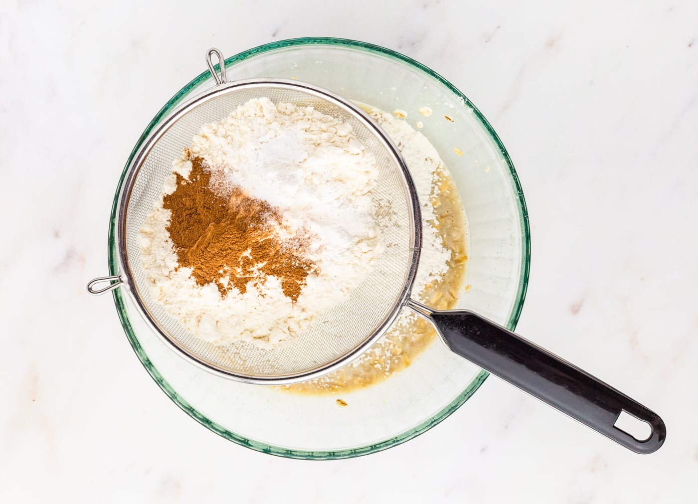 sifting dry ingredients for oatmeal muffins