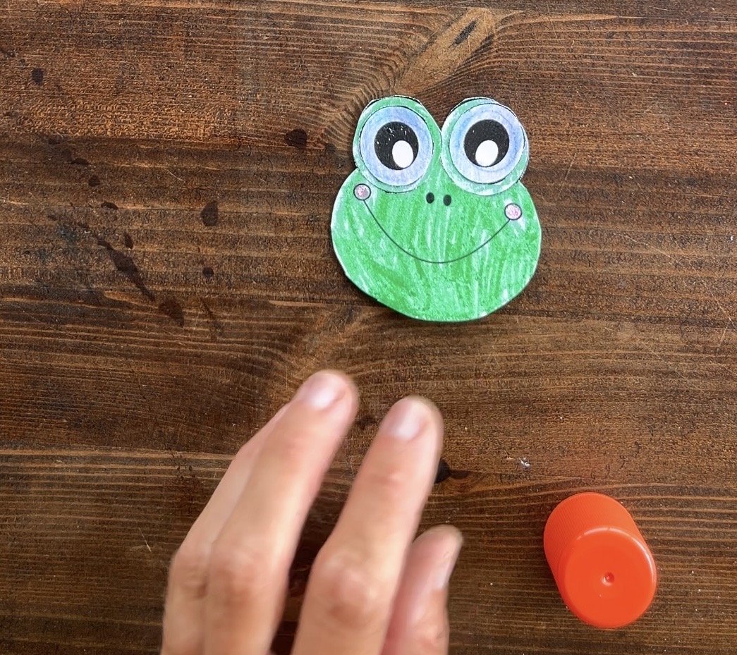 gluing eyes on a frog head paper craft