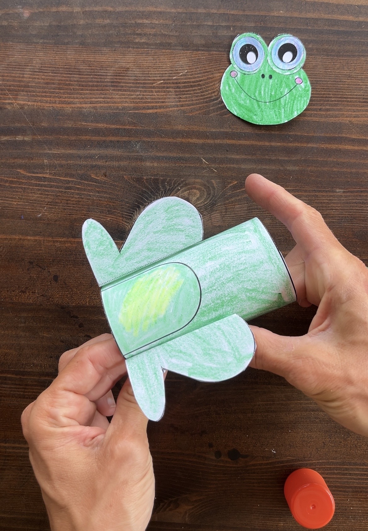gluing the left leg on a 3d paper frog craft