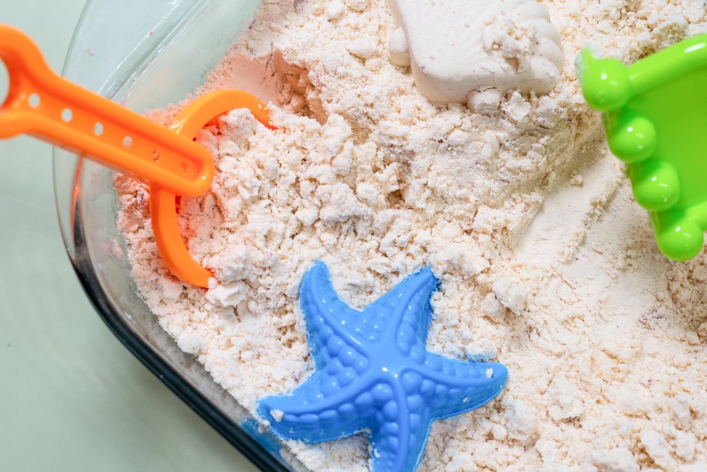 a dish with moon sand and small plastic beach toys