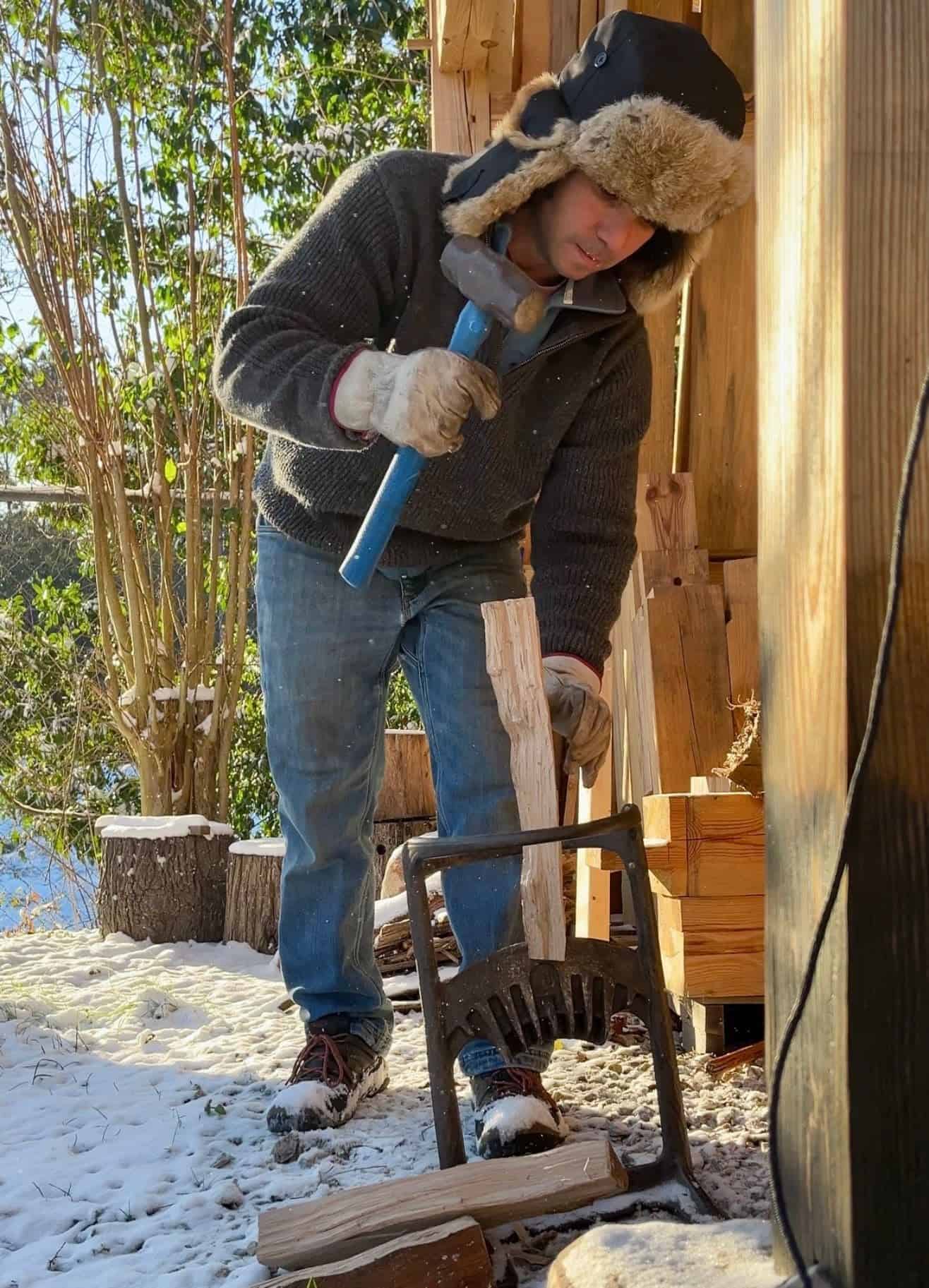 a man waring a hat using a kindling cracker in the snow