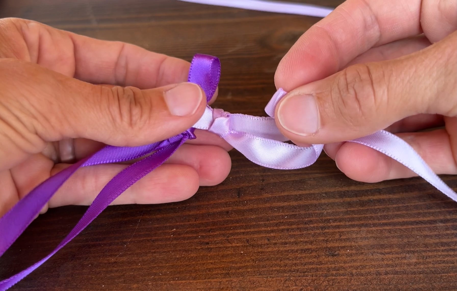 making a loop in light purple ribbon for making a braided ribbon lei