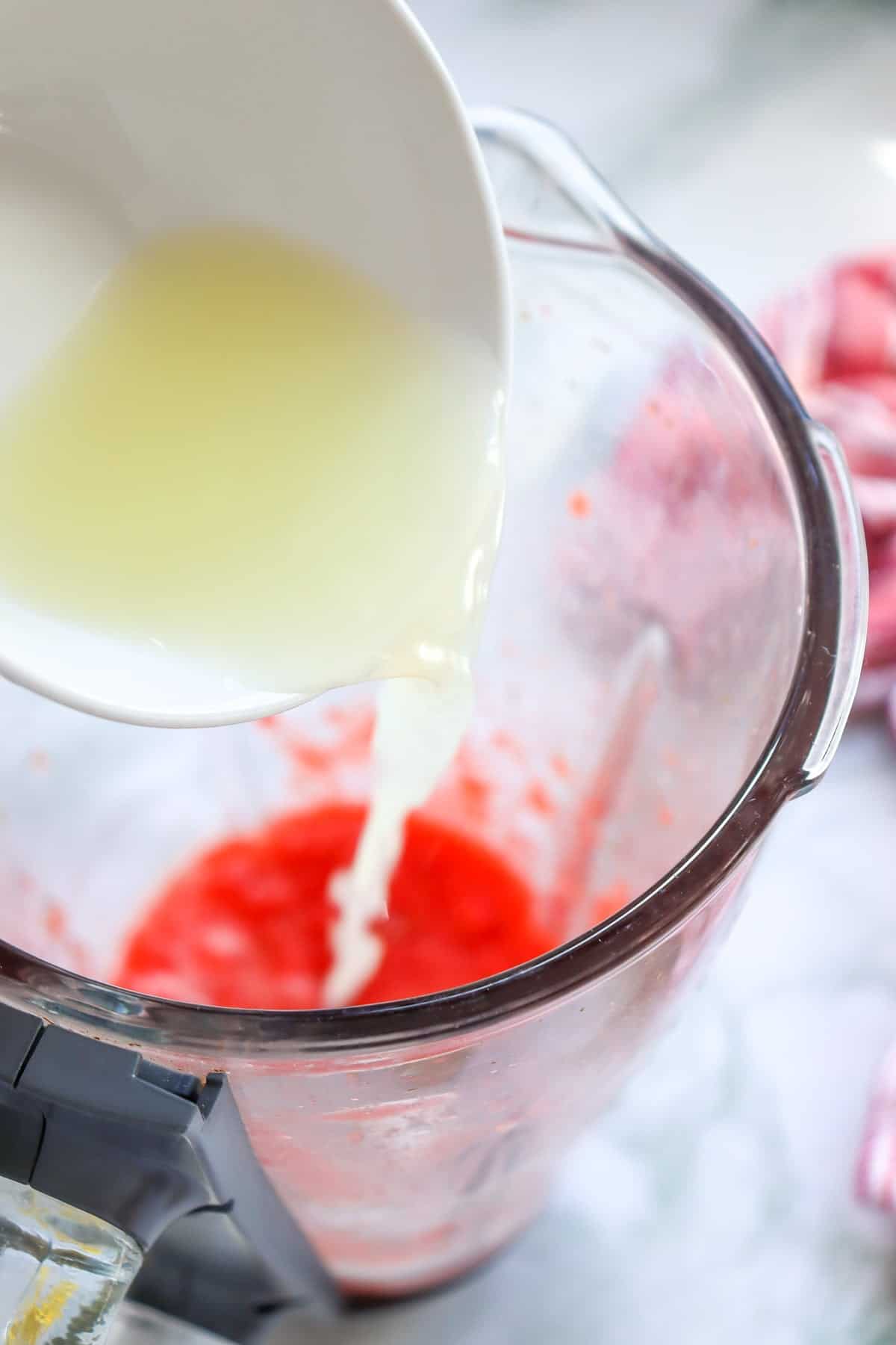 pouring lemon juice into a pitcher to make strawberry lemonade