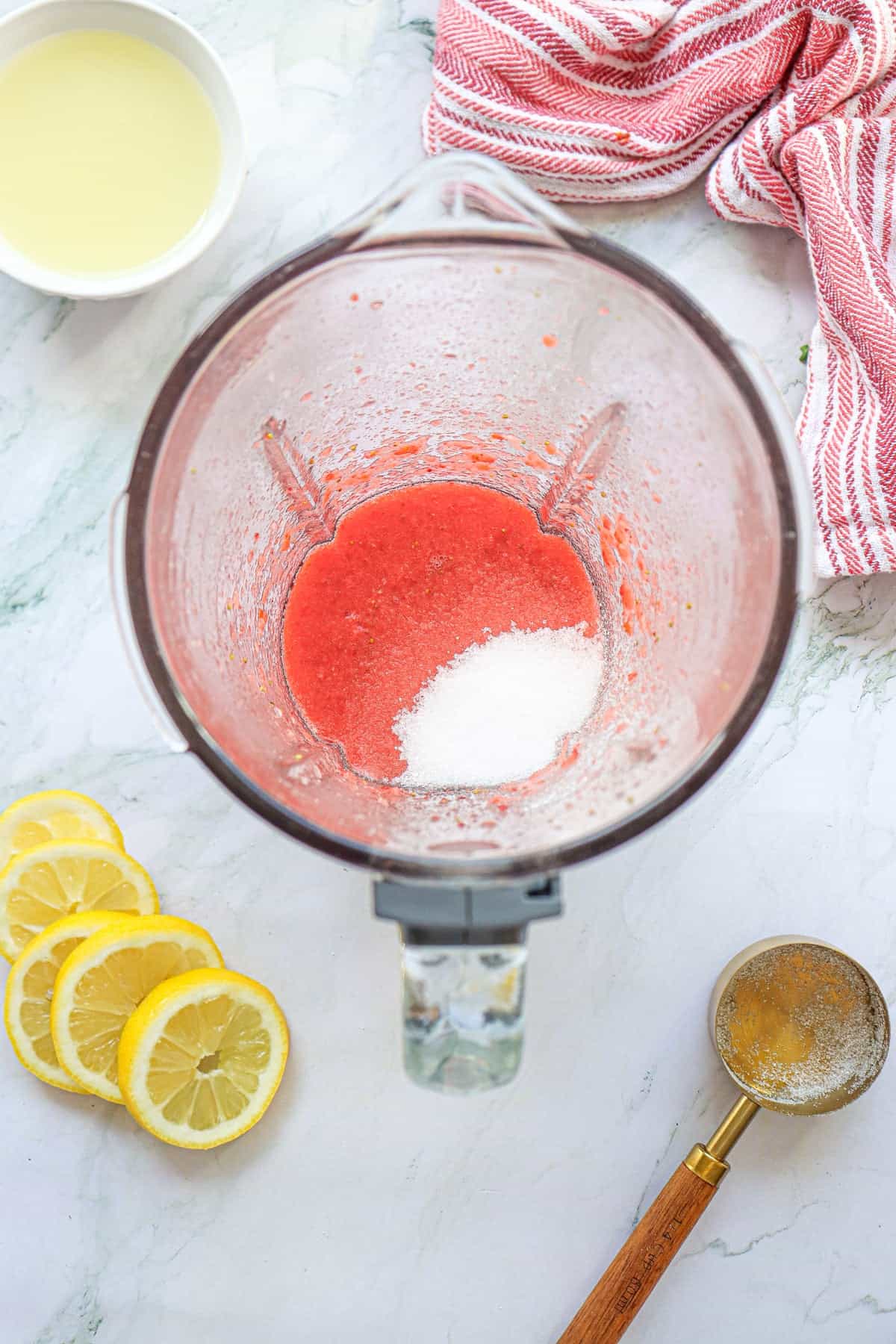 adding sugar to strawberry puree in a blender