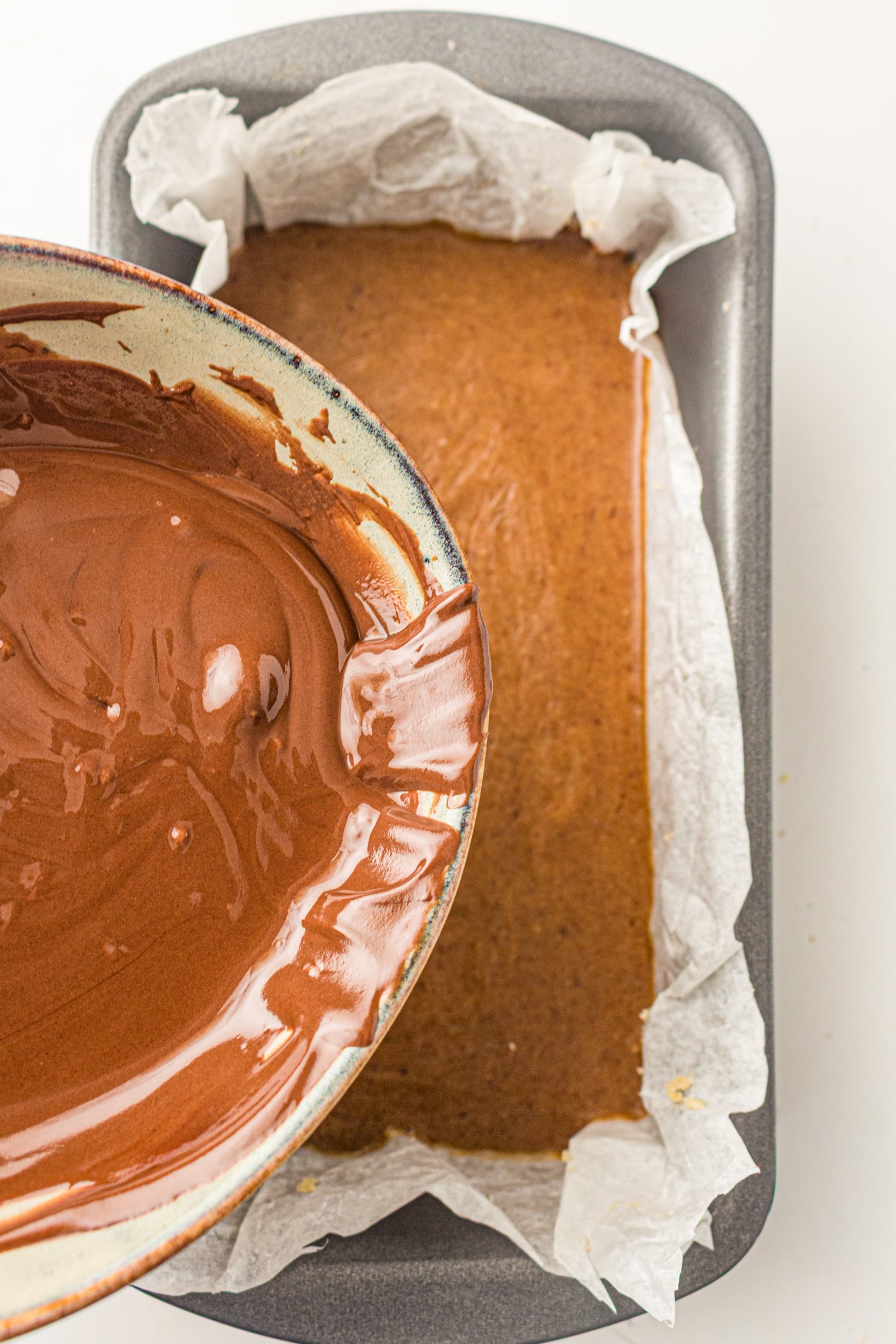 pouring melted chocolate on ingredients for gluten free copycat twix bars