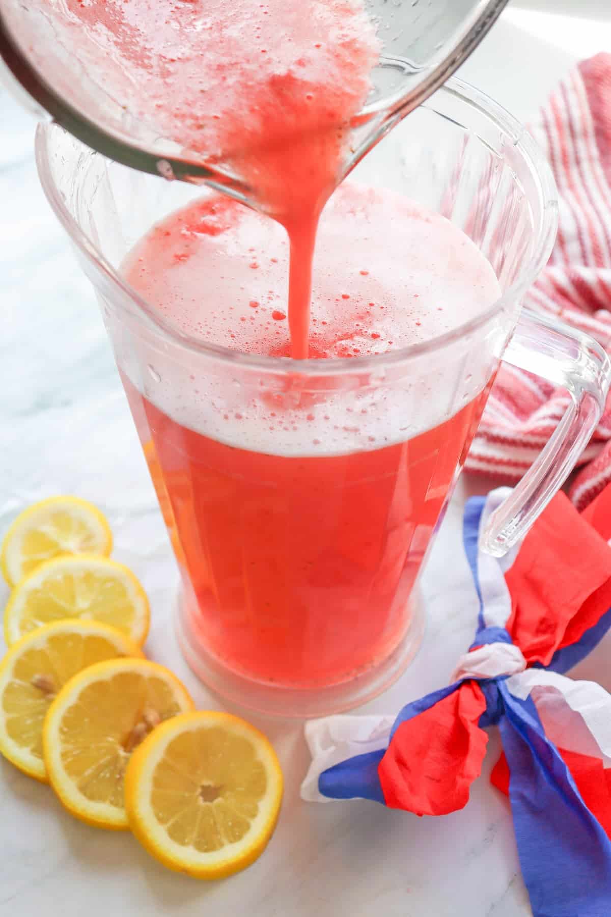 pouring strawberry lemonade form a blender into a pitcher