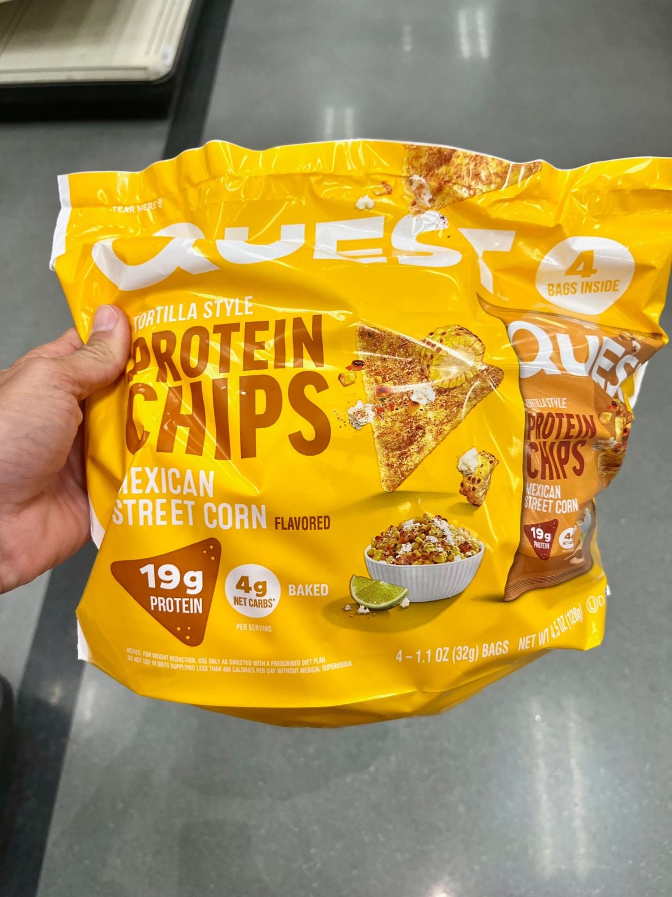 a hand holding a large bag of Quest protein chips