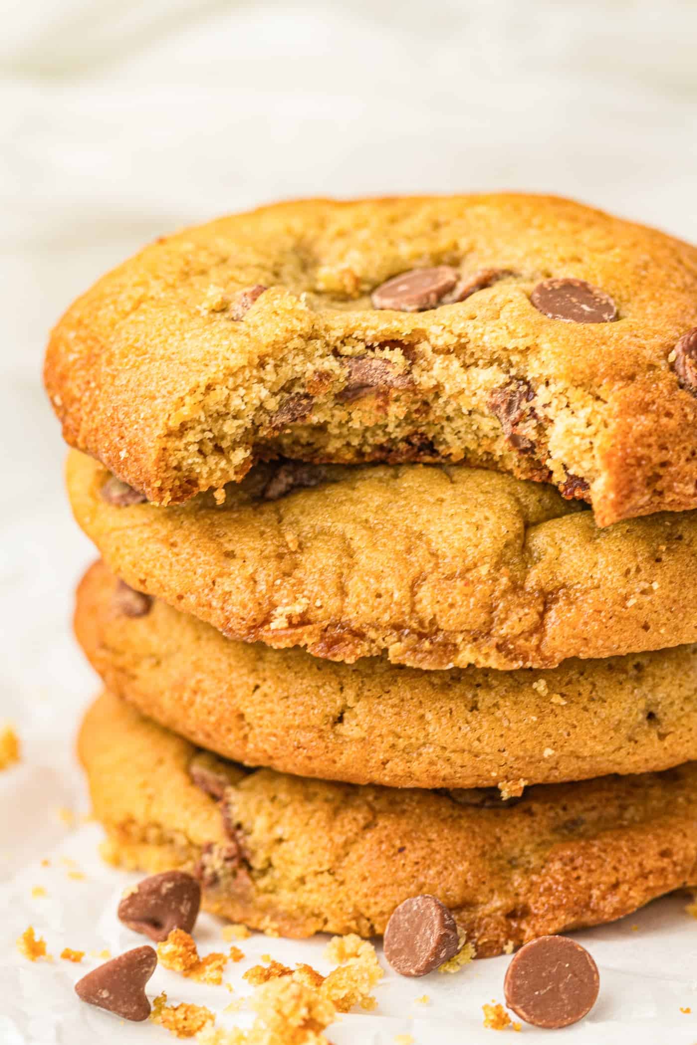 a stack of bakes chocolate chip cookies. The top one is missing a bite.