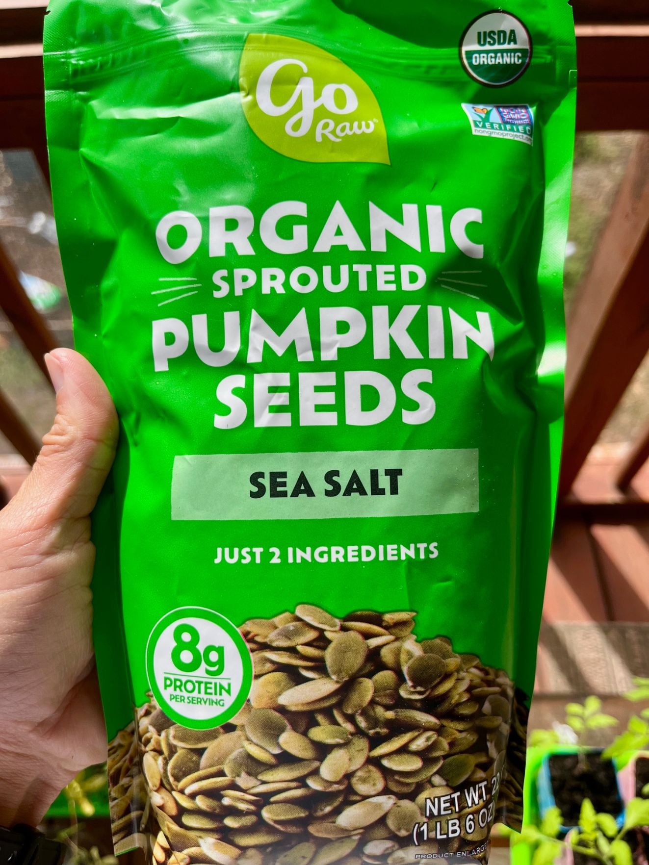 a gain holding a large bag of sported pumpkin seeds
