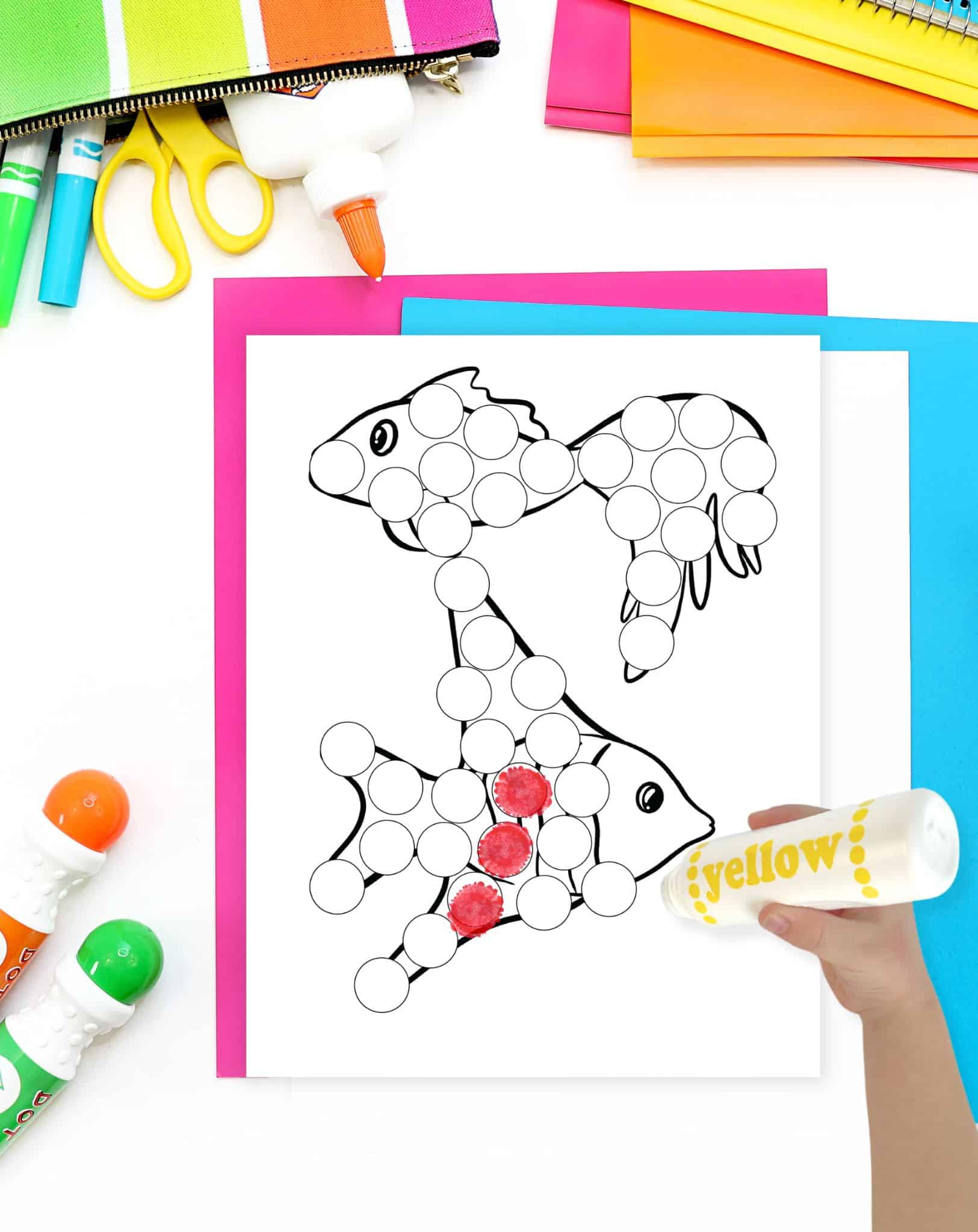 a hadn't with a yellow dauber marker preparing to color a dot marker coloring page showing fish