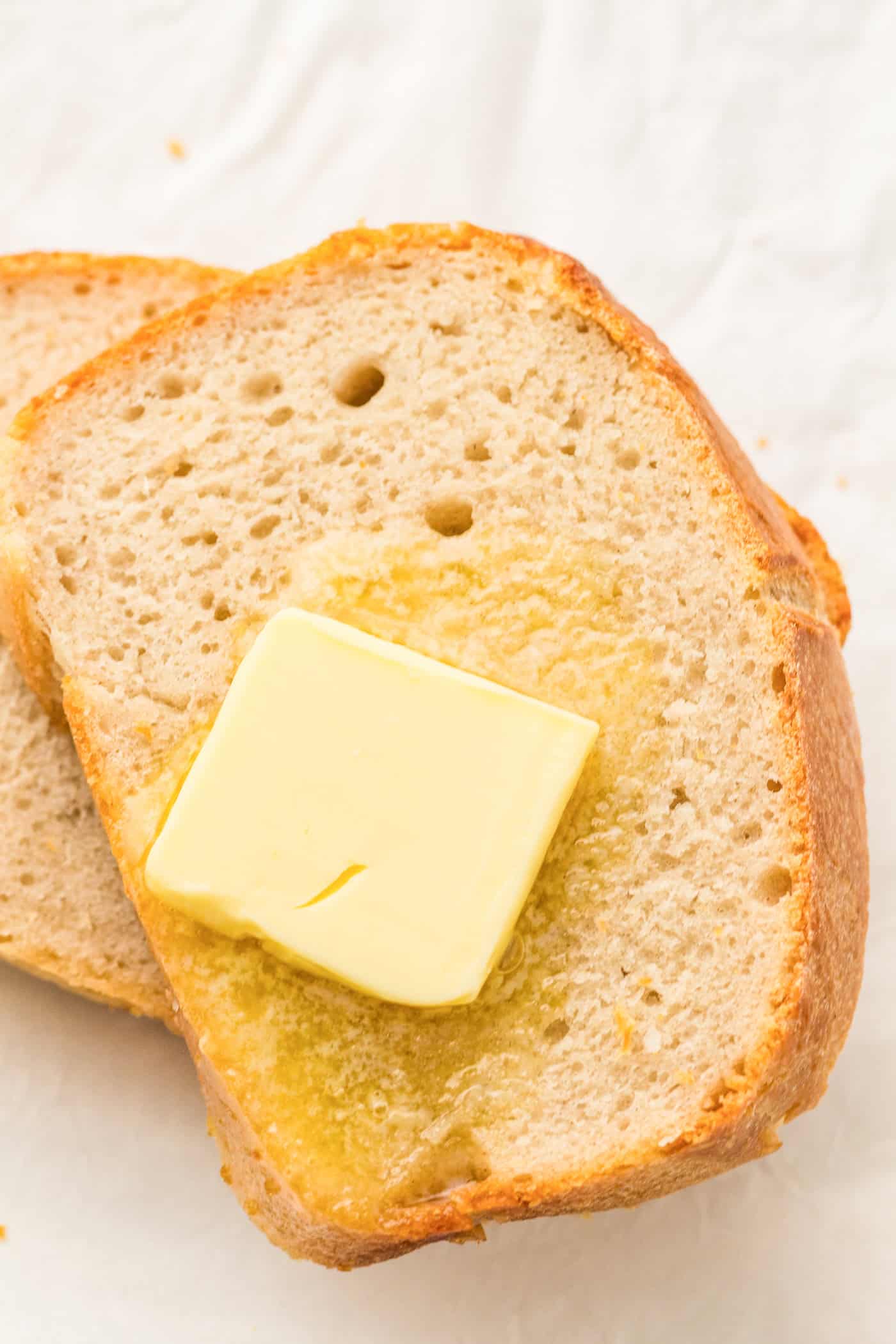a top down photo of slices of sourdough sandwich bread with melting butter on top
