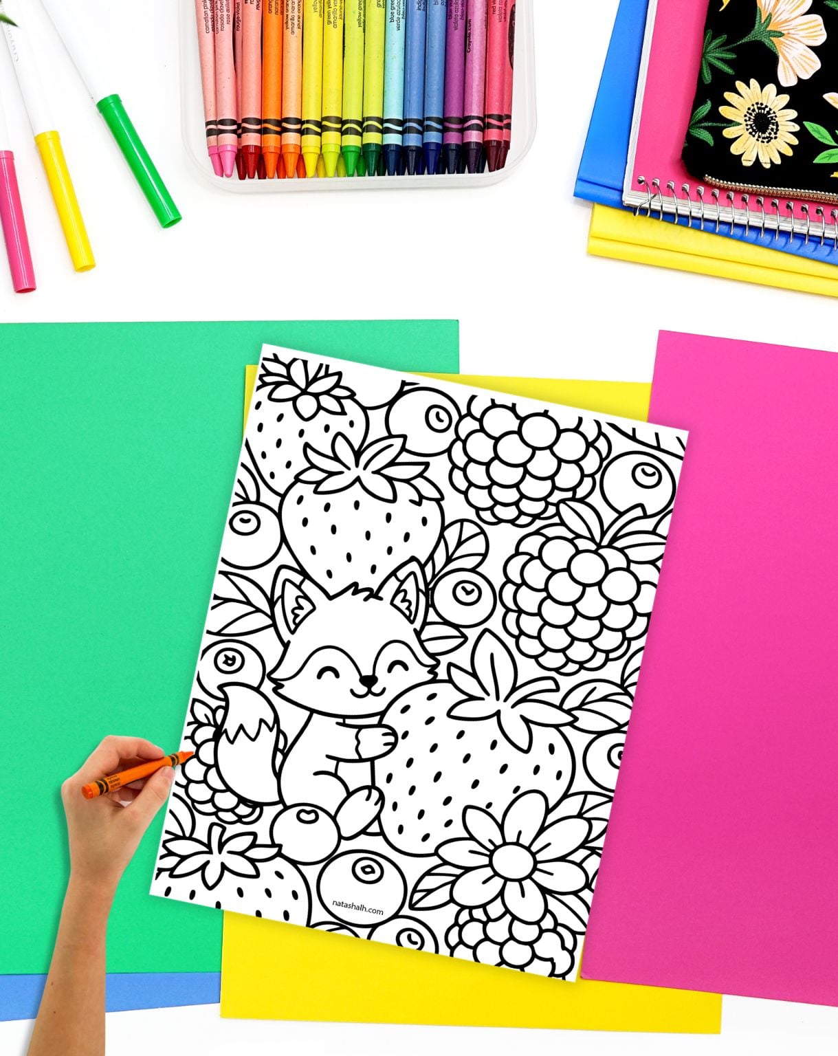 a hand with a crayon preparing to color a cute strawberry coloring page featuring a fox hugging a strawberry