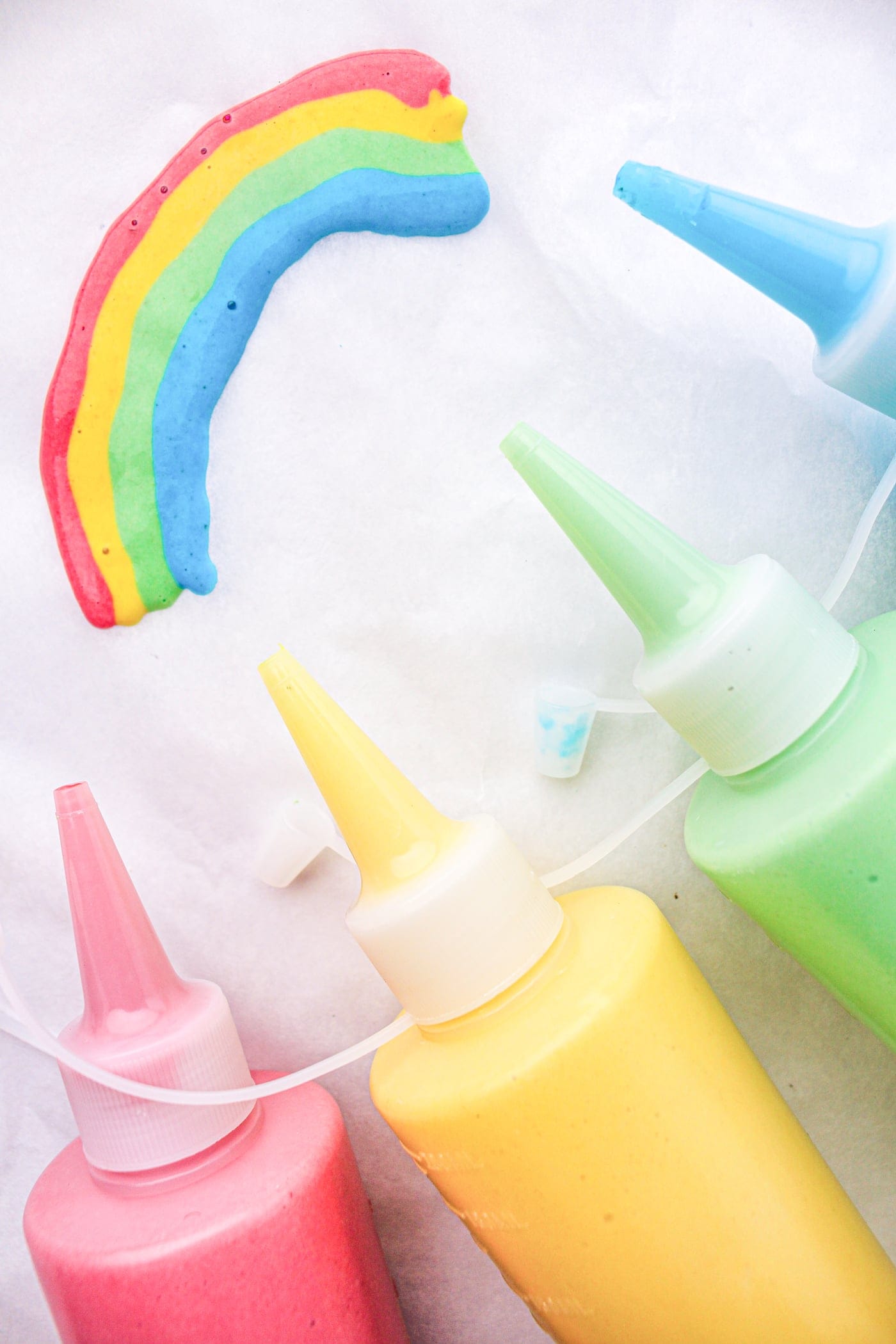 four bottles of diy puffy sidewalk paint with a rainbow painted on paper