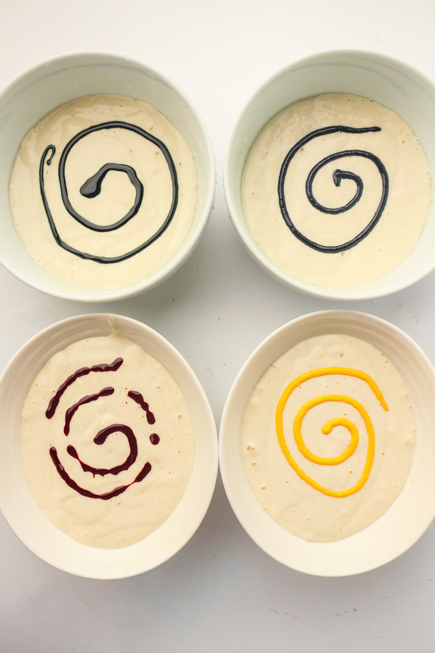 a top down view of four bowls of homemade puffy sidewalk paint with food coloring