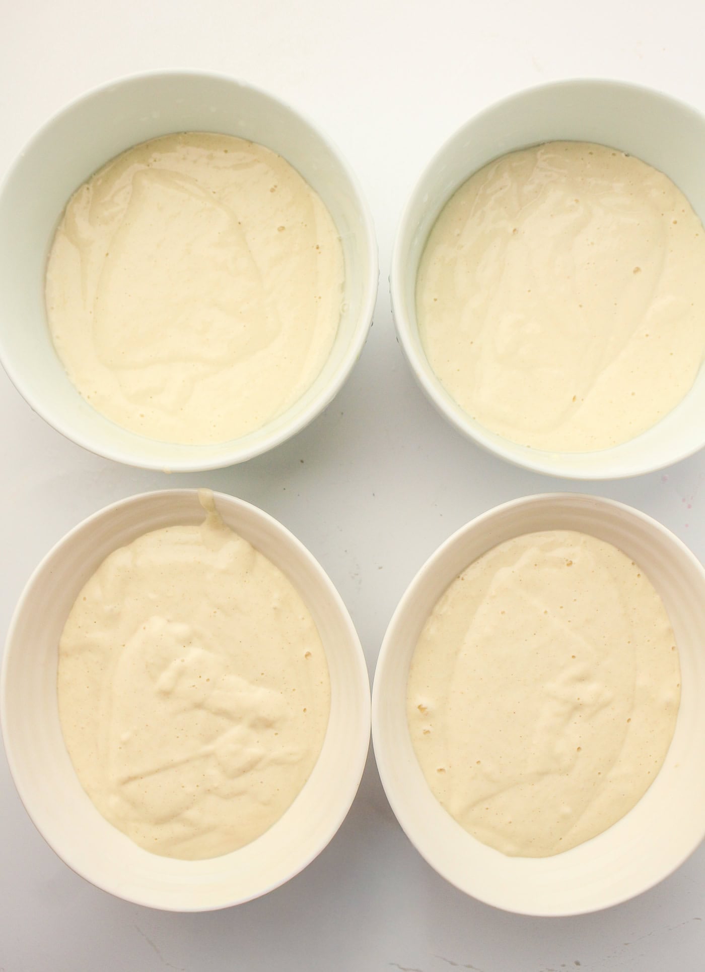 a top down view of four bowls of homemade puffy sidewalk paint awaiting coloring