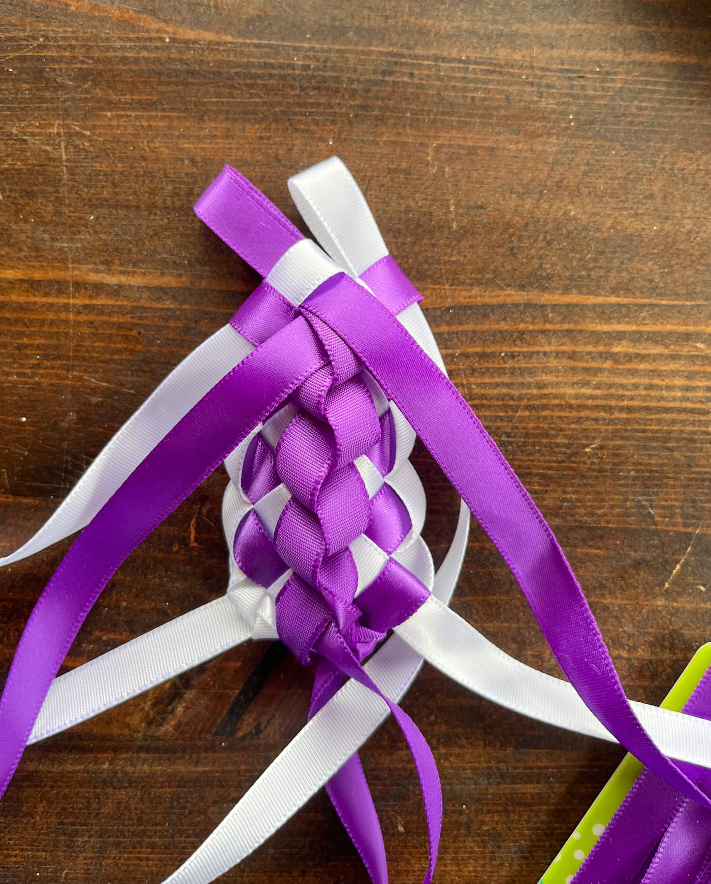 about two inches of completed Hawaiian ribbon lei in purple and white