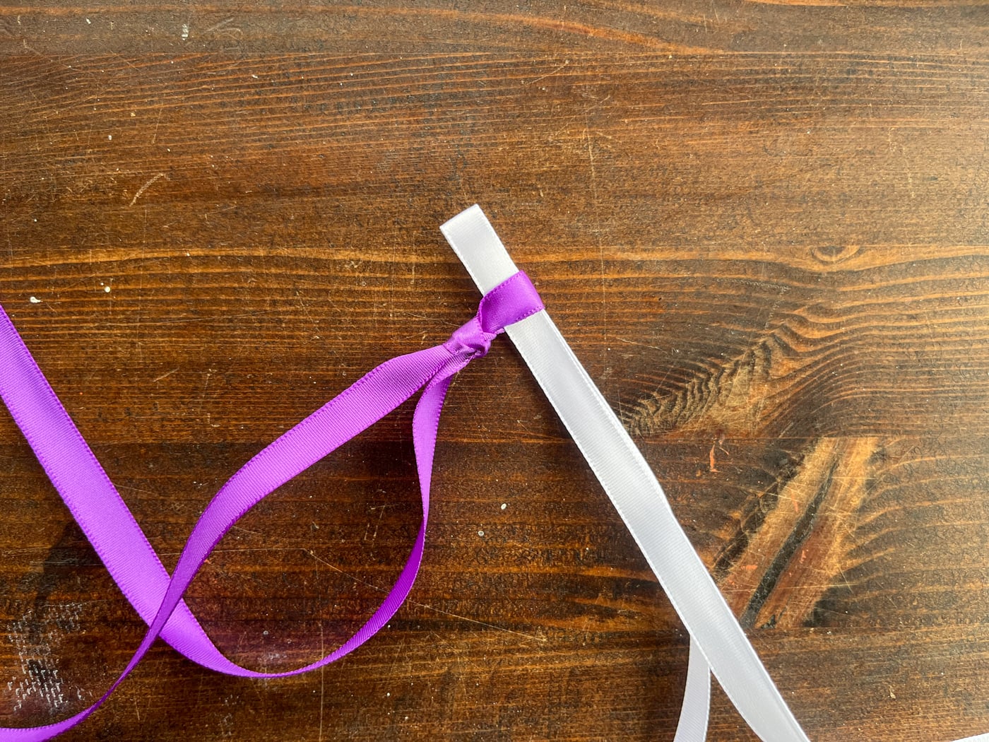 looping a white ribbon through a purple ribbon