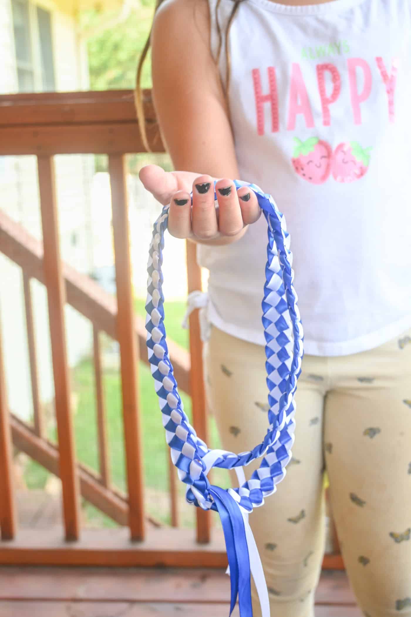 a child holding out a blue and white ribbon lei as a Father's Day gift