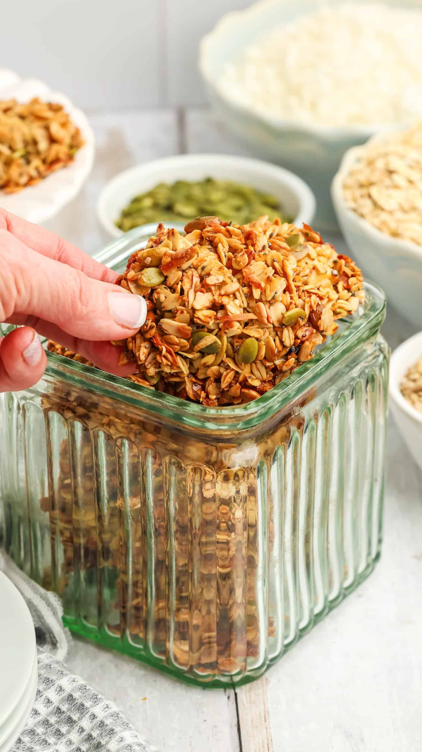 a hand placing a granola cookie in a glass jar