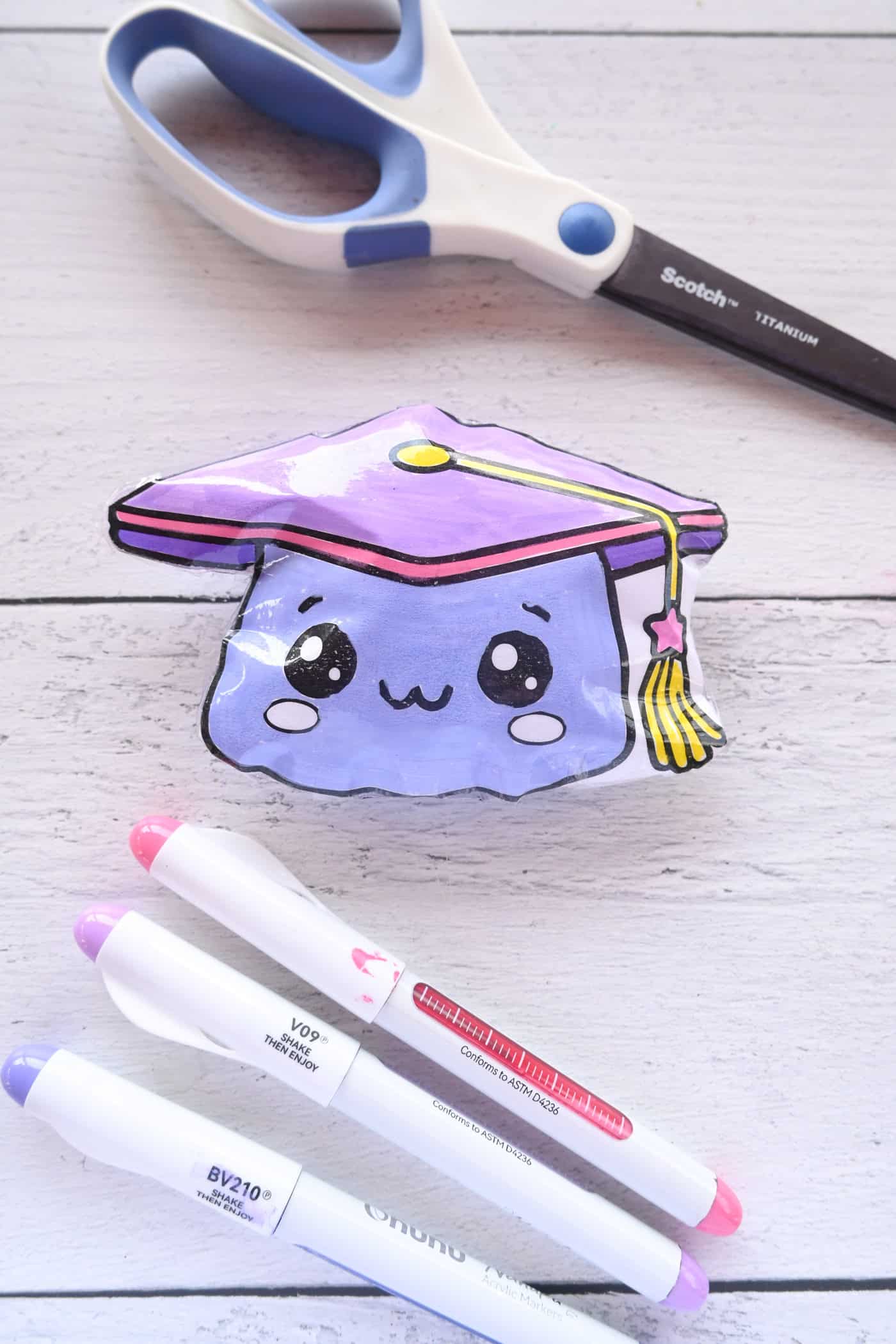 a paper graduation cap squishy with scissors and paint markers