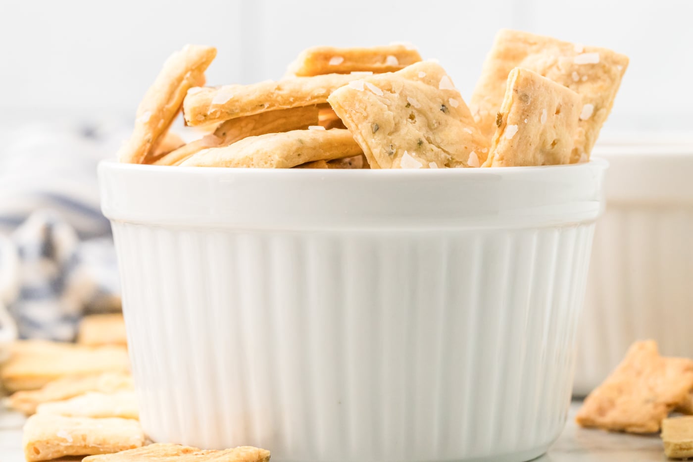 a side view photo of a shite ramekin of sourdough discord crackers