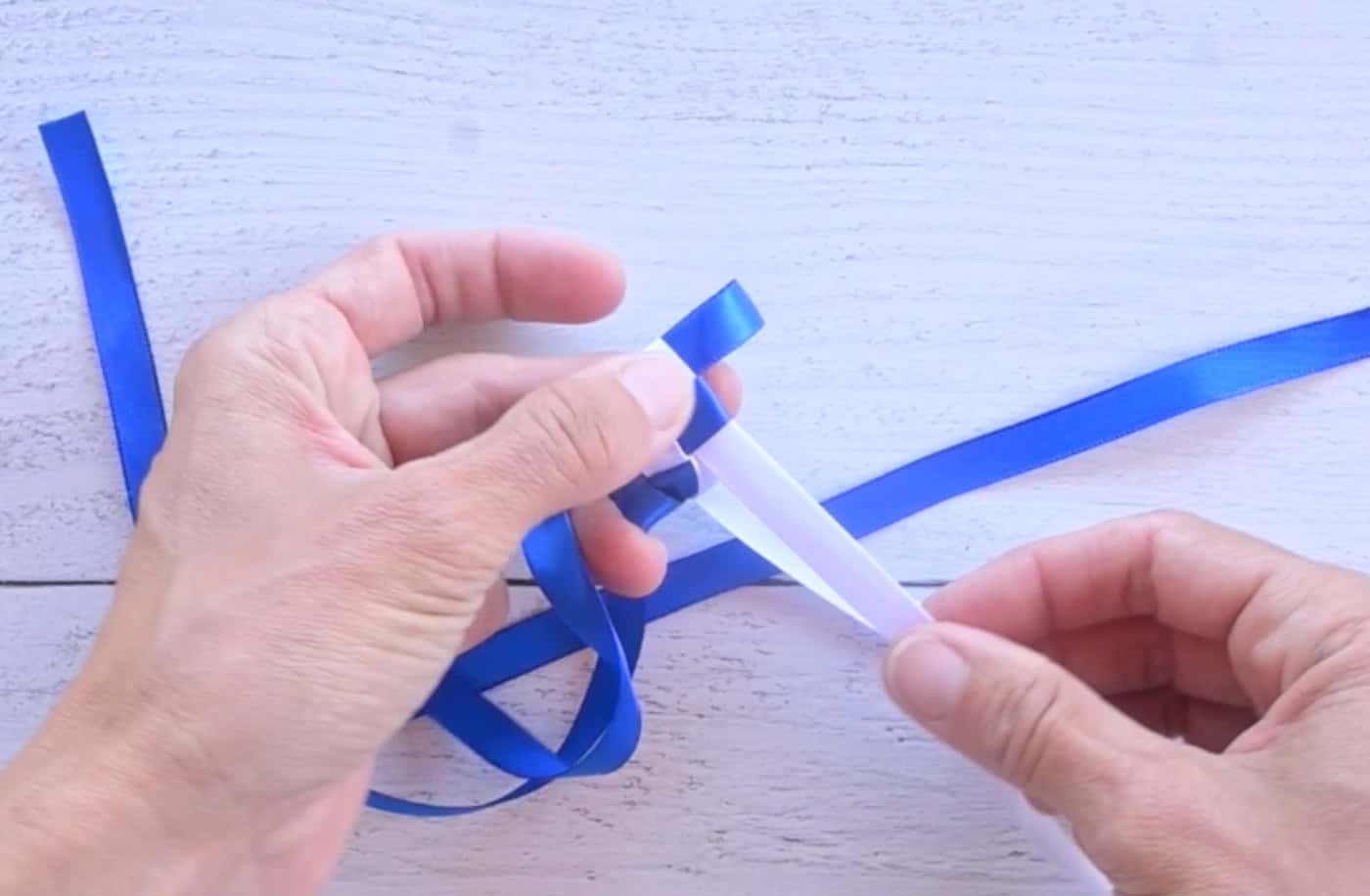 sliding a bloop of blue ribbon through a white ribbon loop