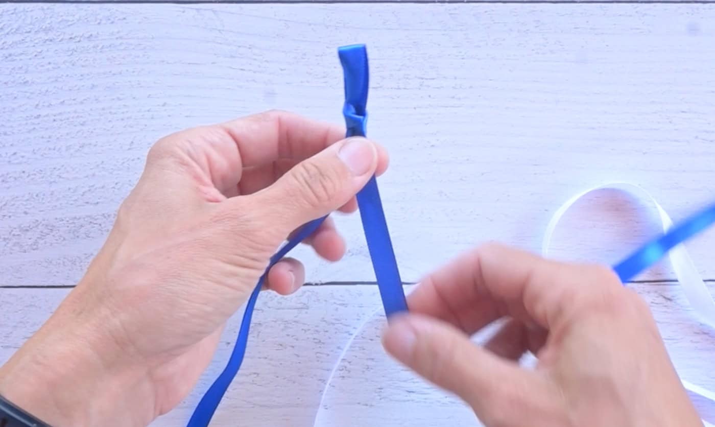 making a slip knot in a piece of blue ribbon