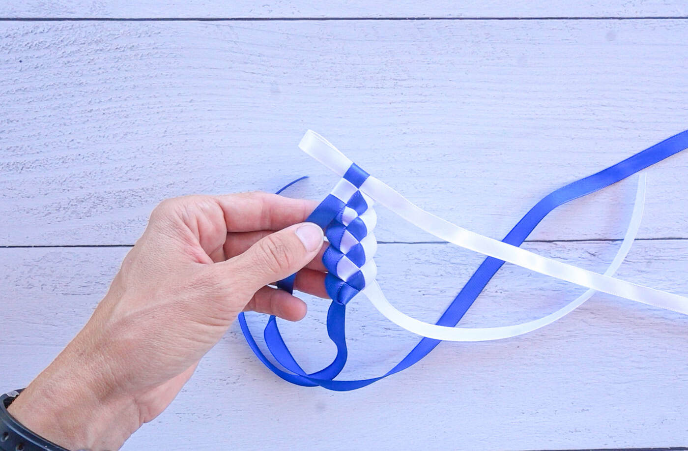 a blue and white ribbon lei in the process of being made.