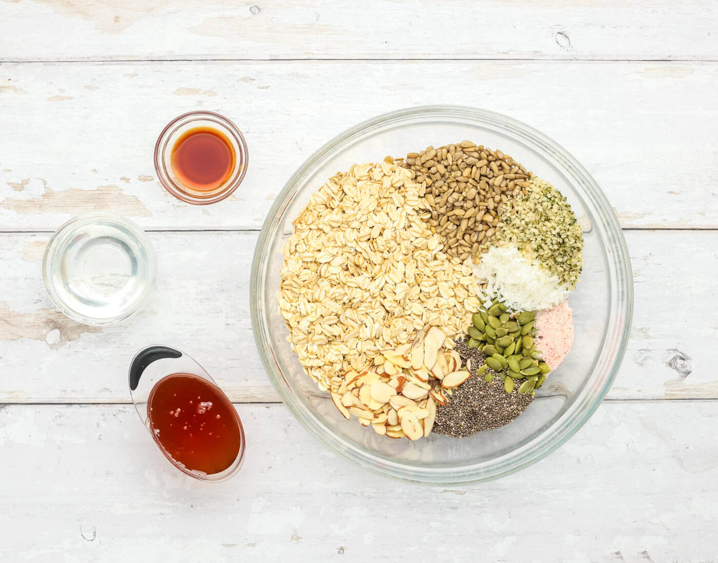 dry ingredients for making granola cookies in a. bowl including oatmeal, nuts, and seeds
