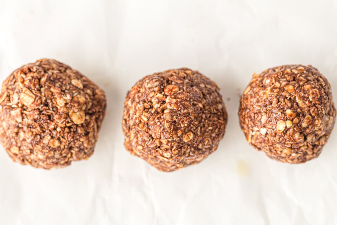 three no bake gluten free energy balls on a piece of parchment paper