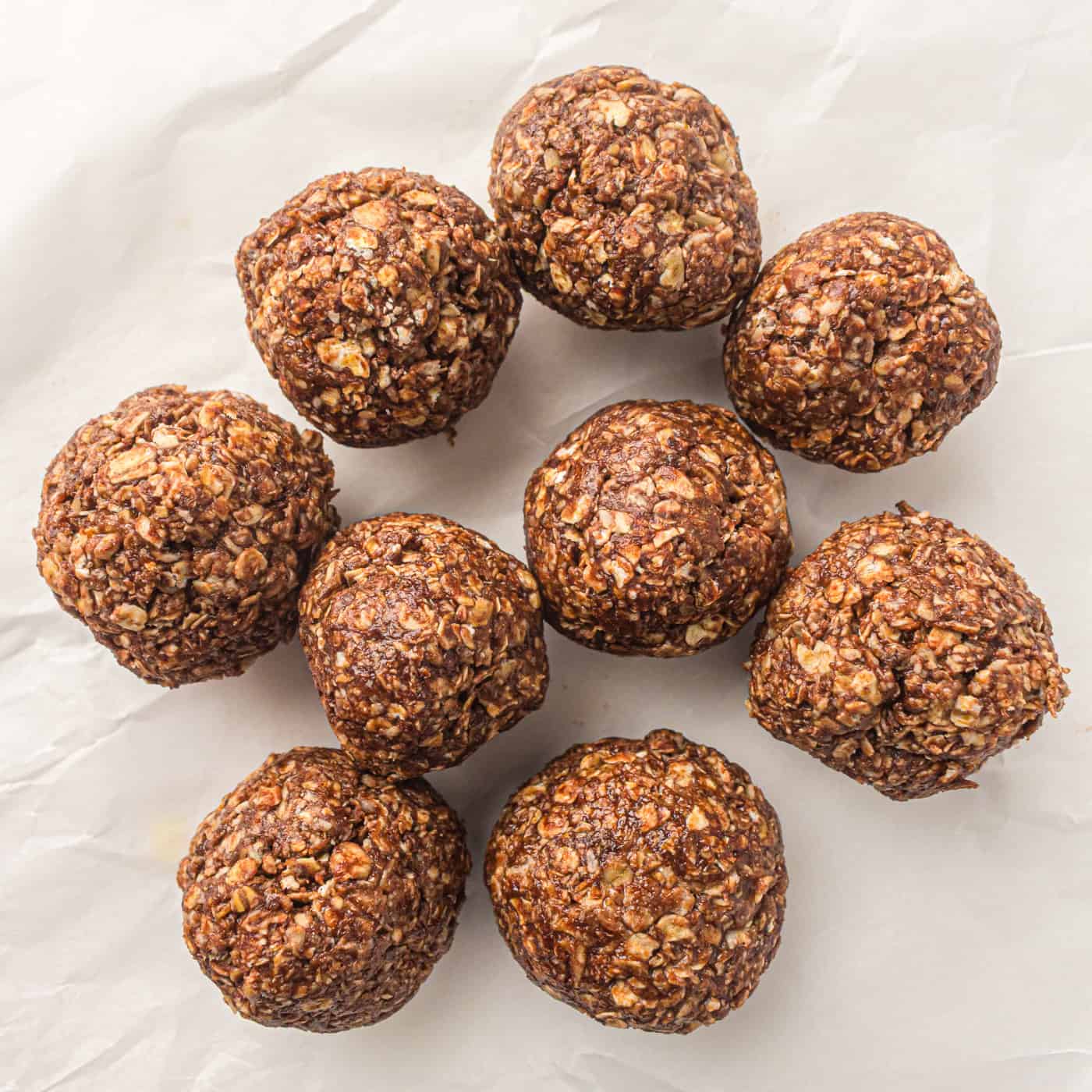 a stack of no bake peanut butter oatmeal energy balls on a piece of parchment paper