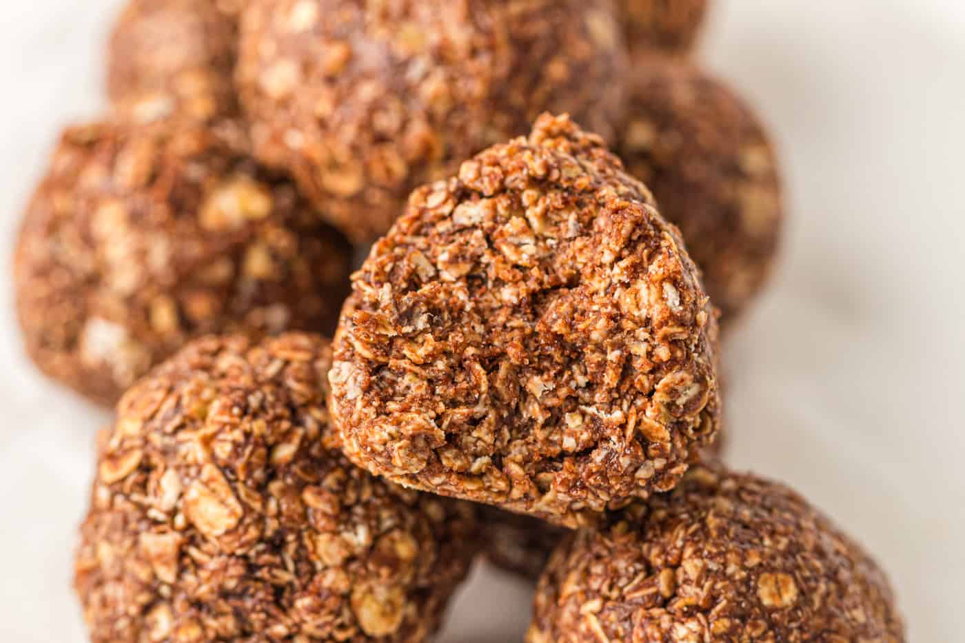 a close up view of no bake peanut butter oatmeal balls. One has a bite taken out of it.