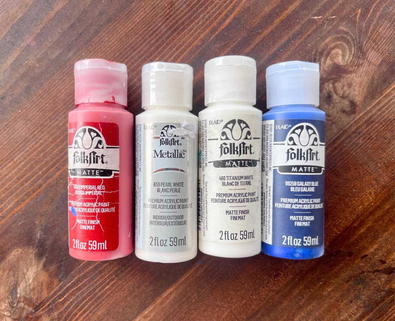 four bottles of folk art paint on a wood table