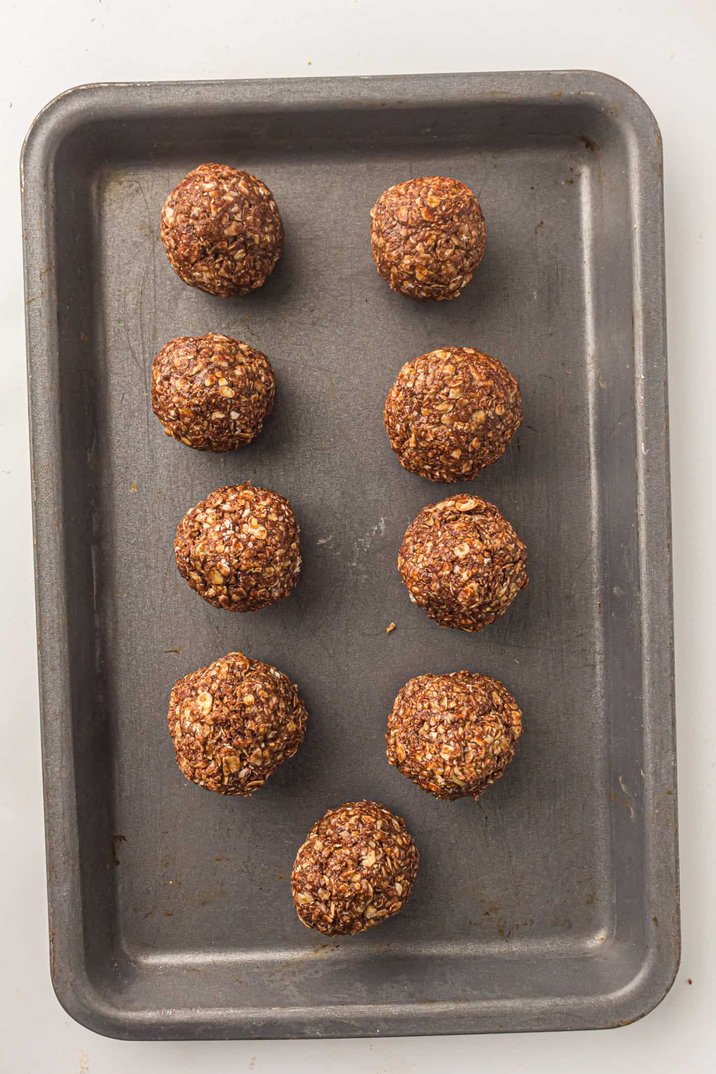 a baking sheet with a dozen no bake oatmeal peanut butter balls