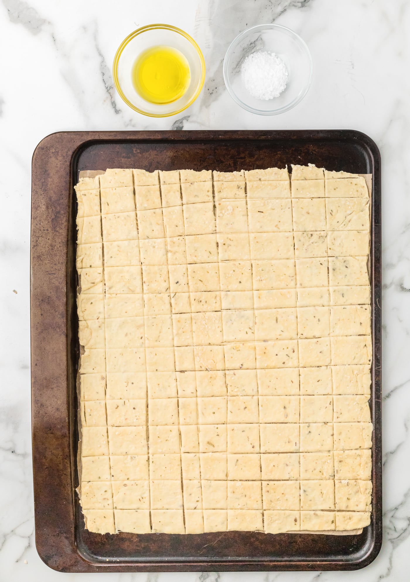 rolled out sourdough discard cracker dough on a baking sheet toping with olive oil and salt