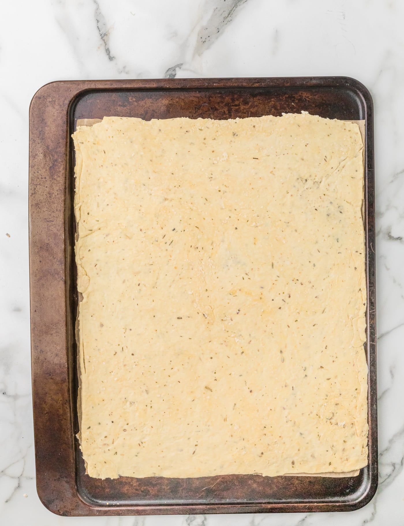 rolled out sourdough discard cracker dough on a baking sheet